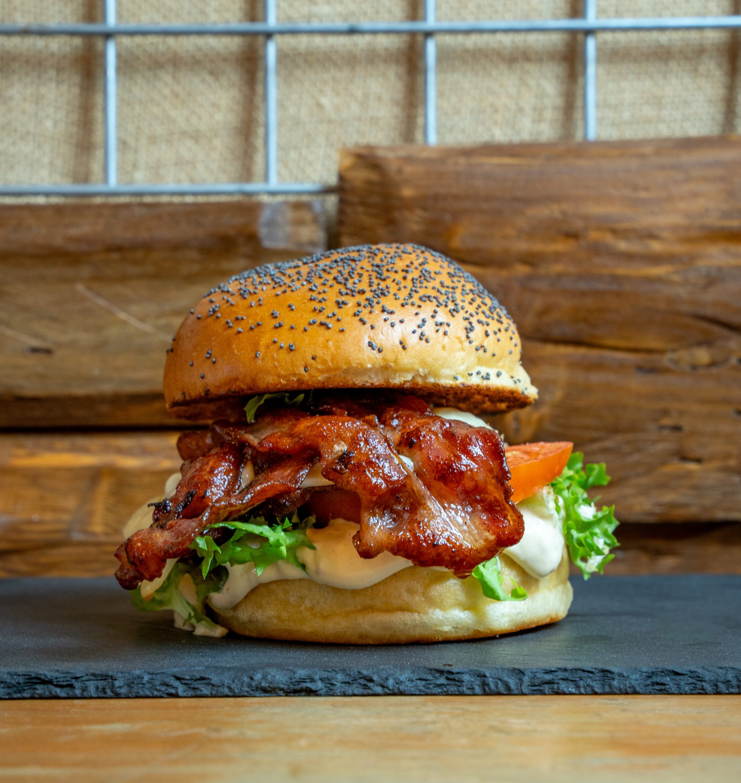Burger de Abe's con bacon crujiente, lechuga y tomate sobre pizarra