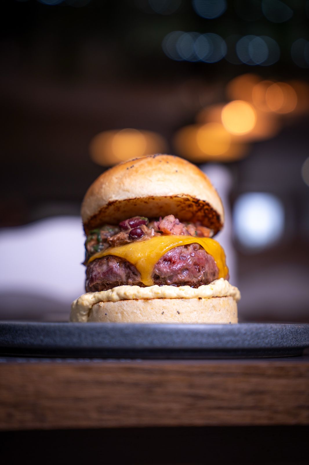Burger de Abe's con cheddar fundido, iluminada sobre el fondo cálido del local