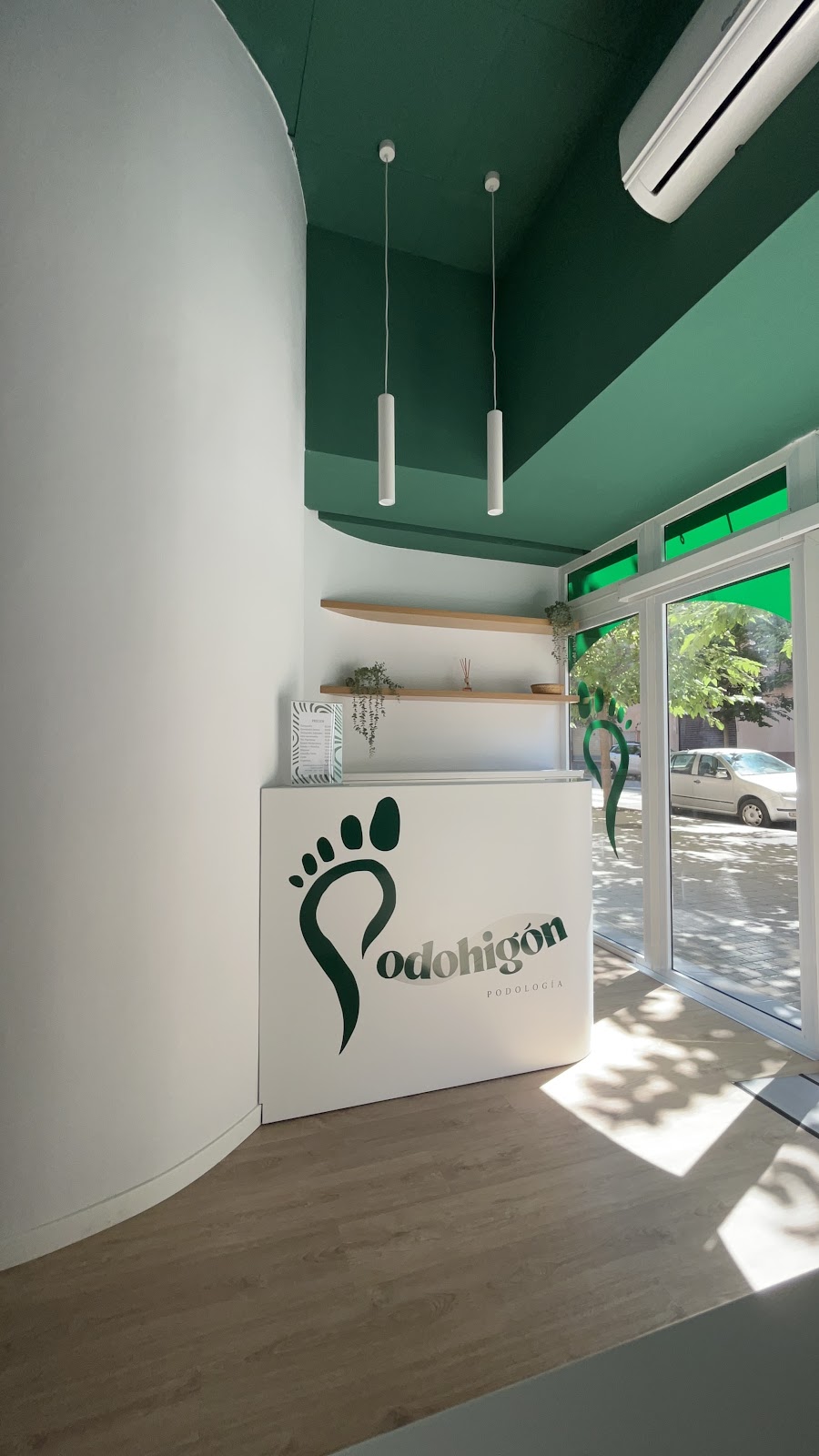 Interior de la clínica Podohigón: mostrador blanco con el logo y techo verde